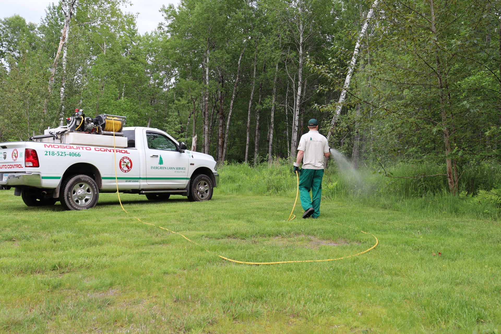 A man is spraying a field with a truck in the background.