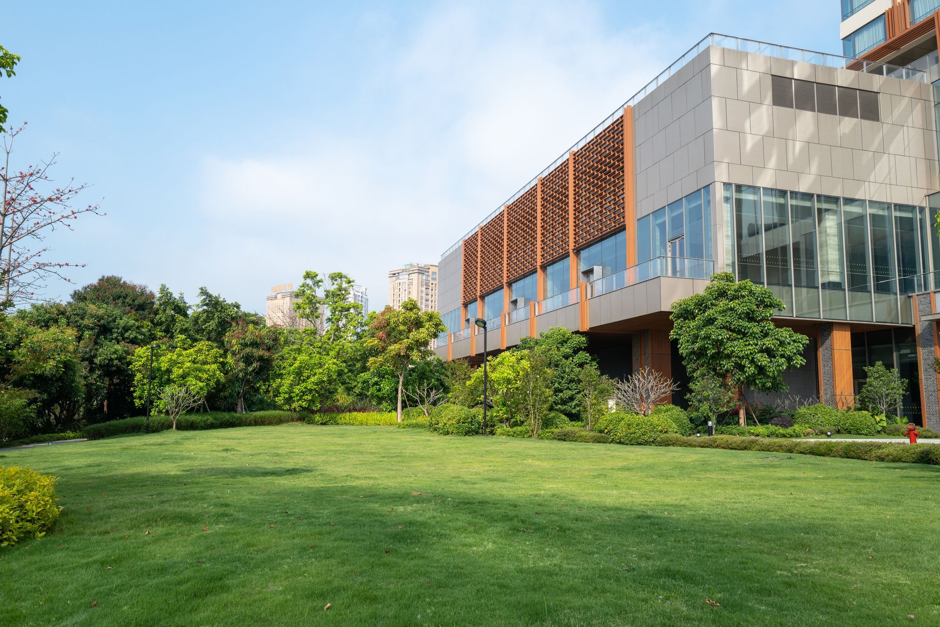An empty green meadow in front of a modern commercial building.