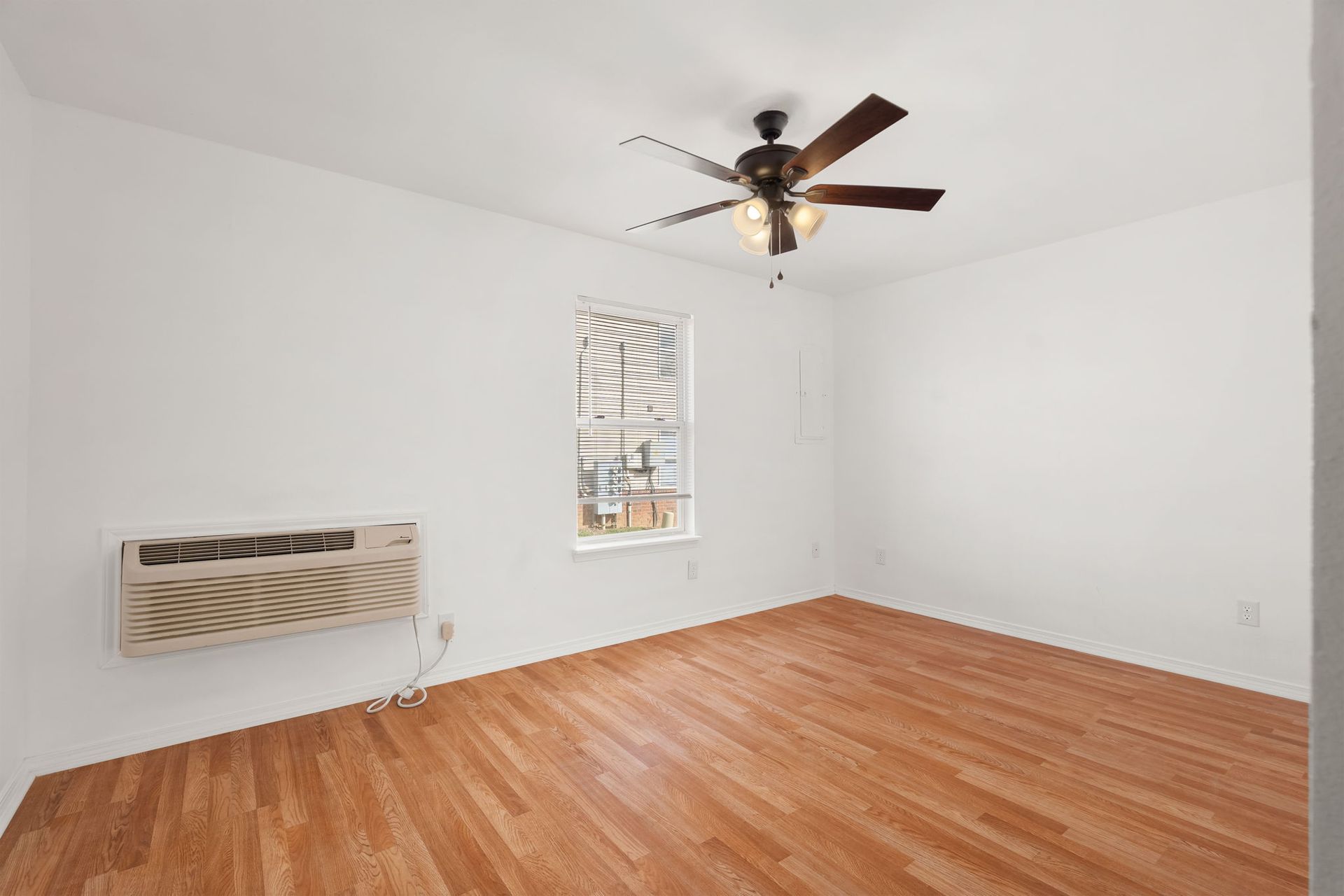 An empty bedroom with hardwood floors and a ceiling fan.