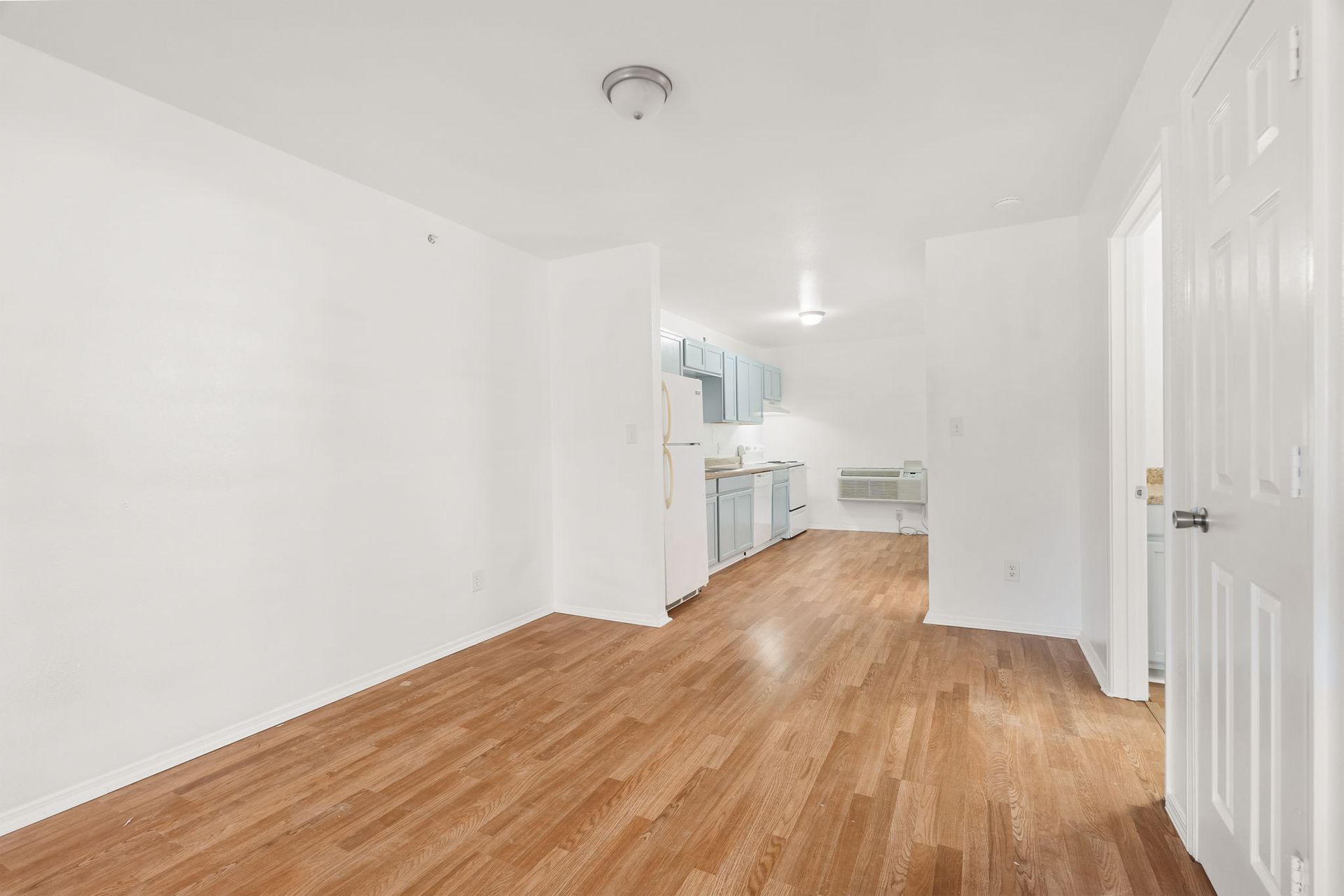An empty room with hardwood floors and white walls