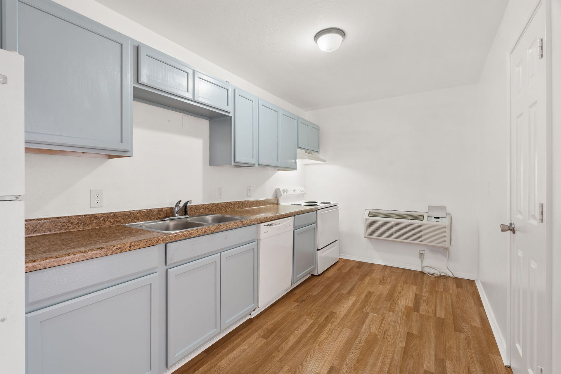 A kitchen with gray cabinets and a wooden floor