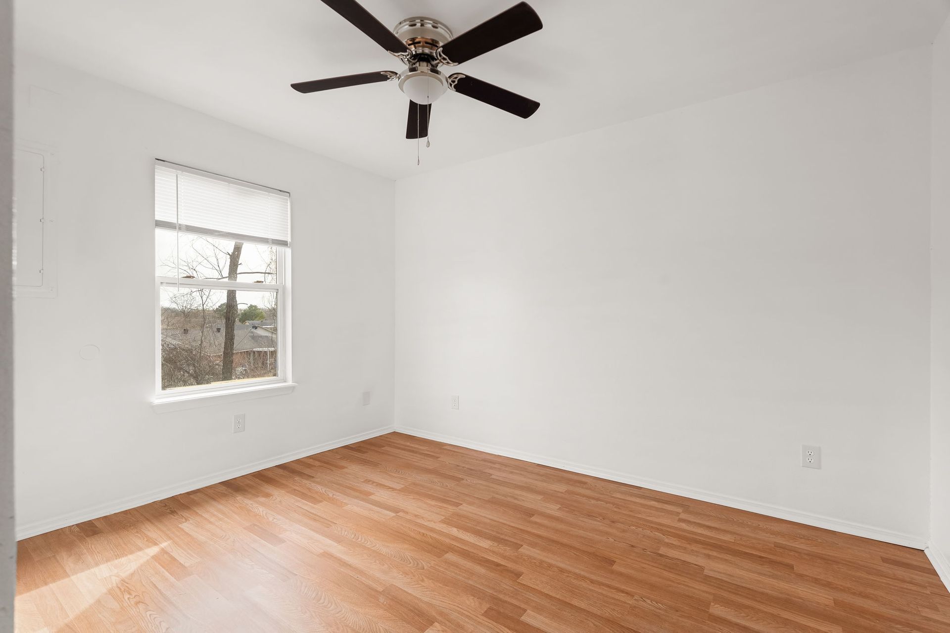 An empty bedroom with hardwood floors and a ceiling fan.