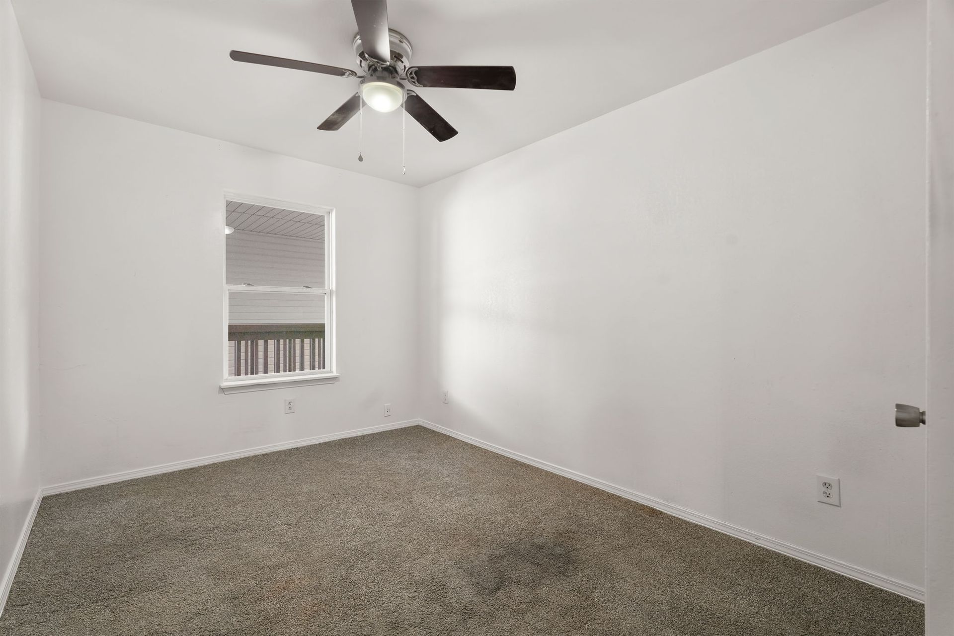 An empty bedroom with a ceiling fan and a window.