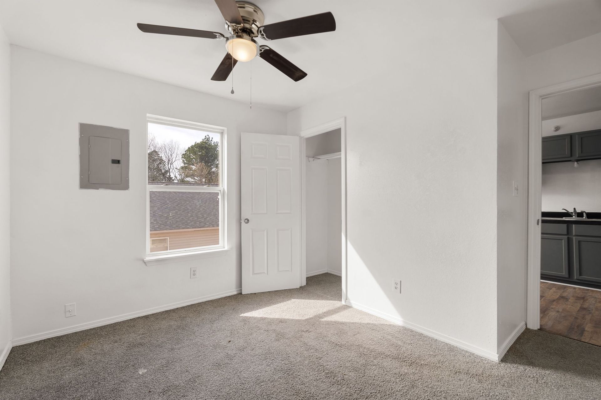 An empty room with a ceiling fan and a window.