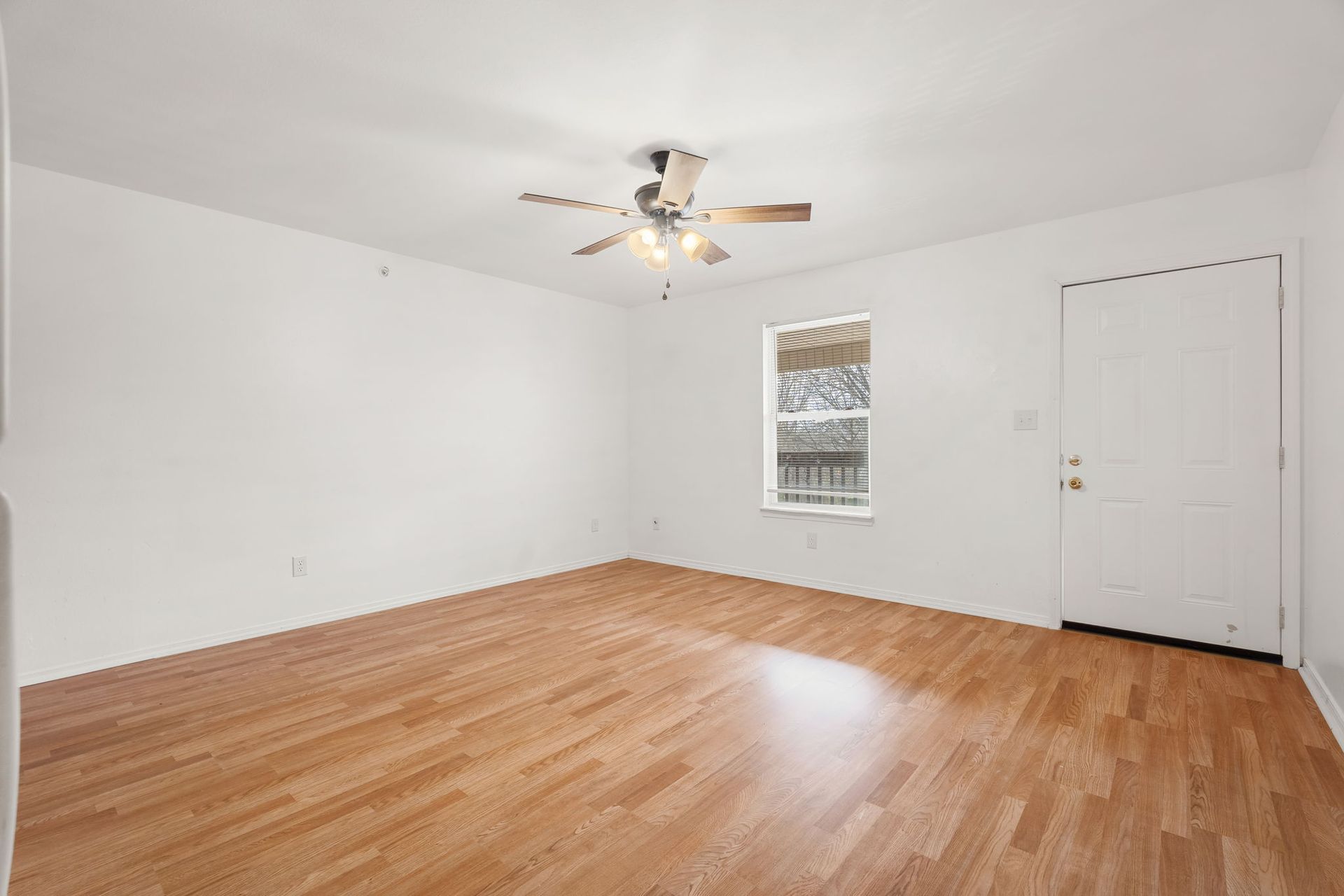 An empty living room with hardwood floors and a ceiling fan.