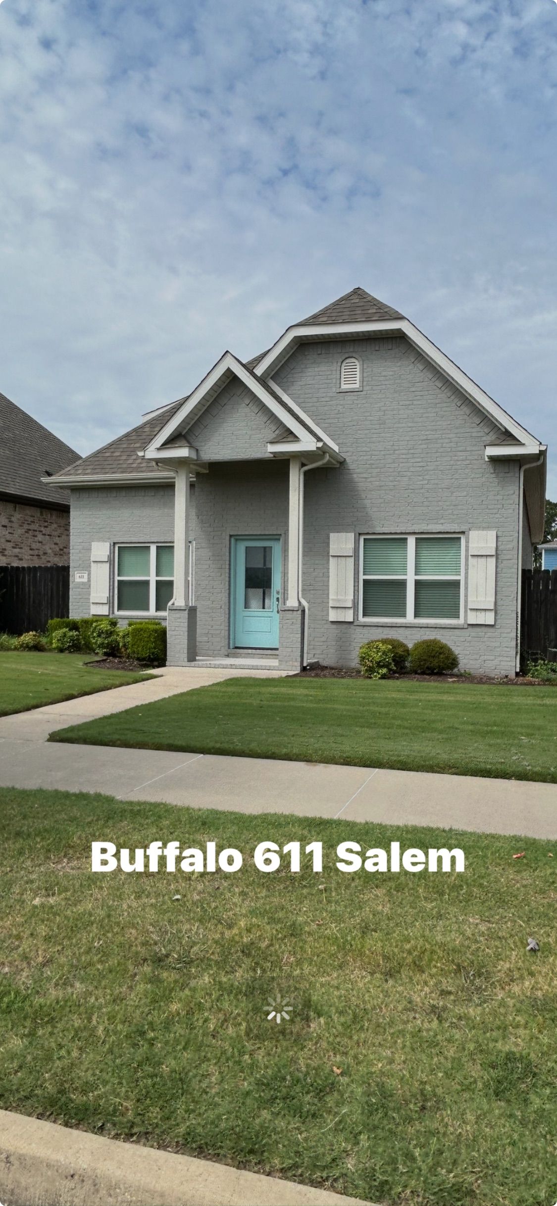 A gray house with a blue door and white shutters. 