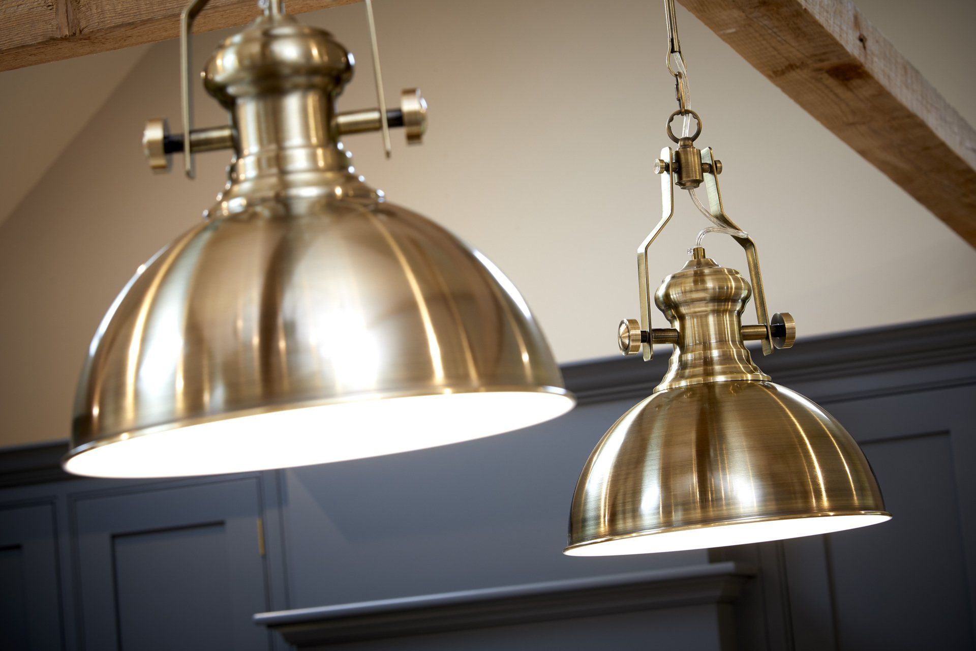 Two brass pendant lights are hanging from the ceiling in a kitchen.