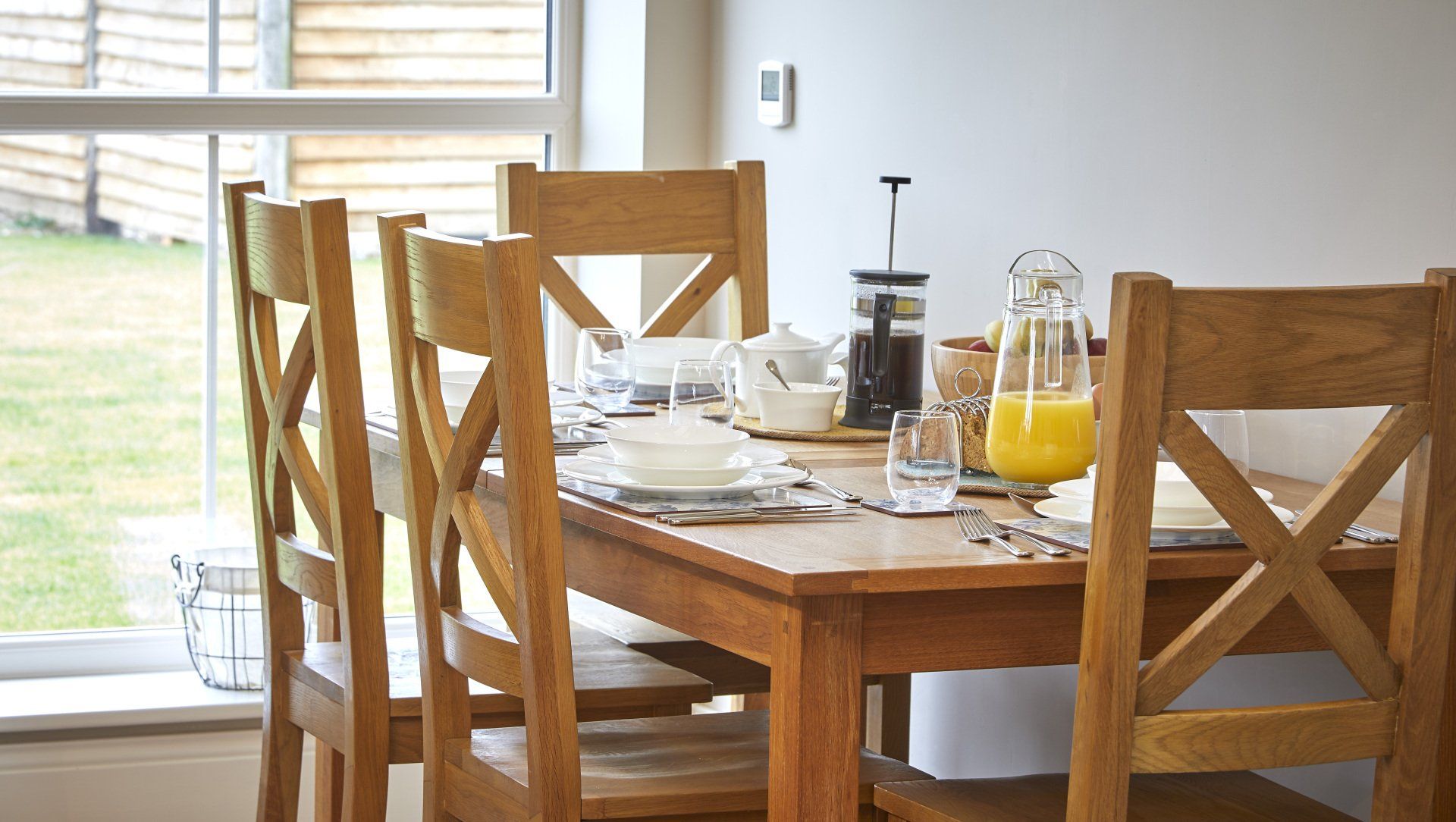 A wooden dining table with a pitcher of orange juice on it.