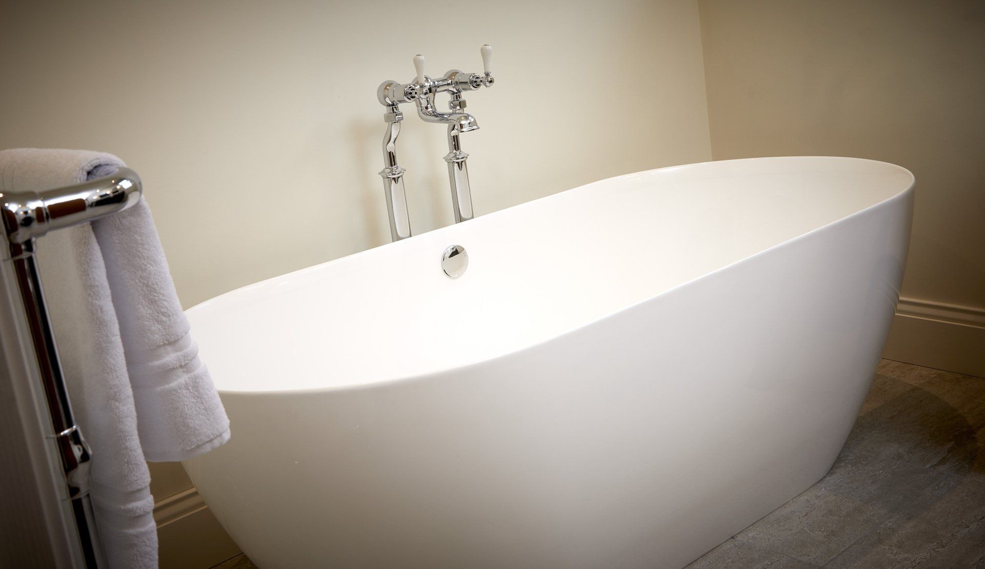 A white bathtub is sitting in a bathroom next to a towel rack.