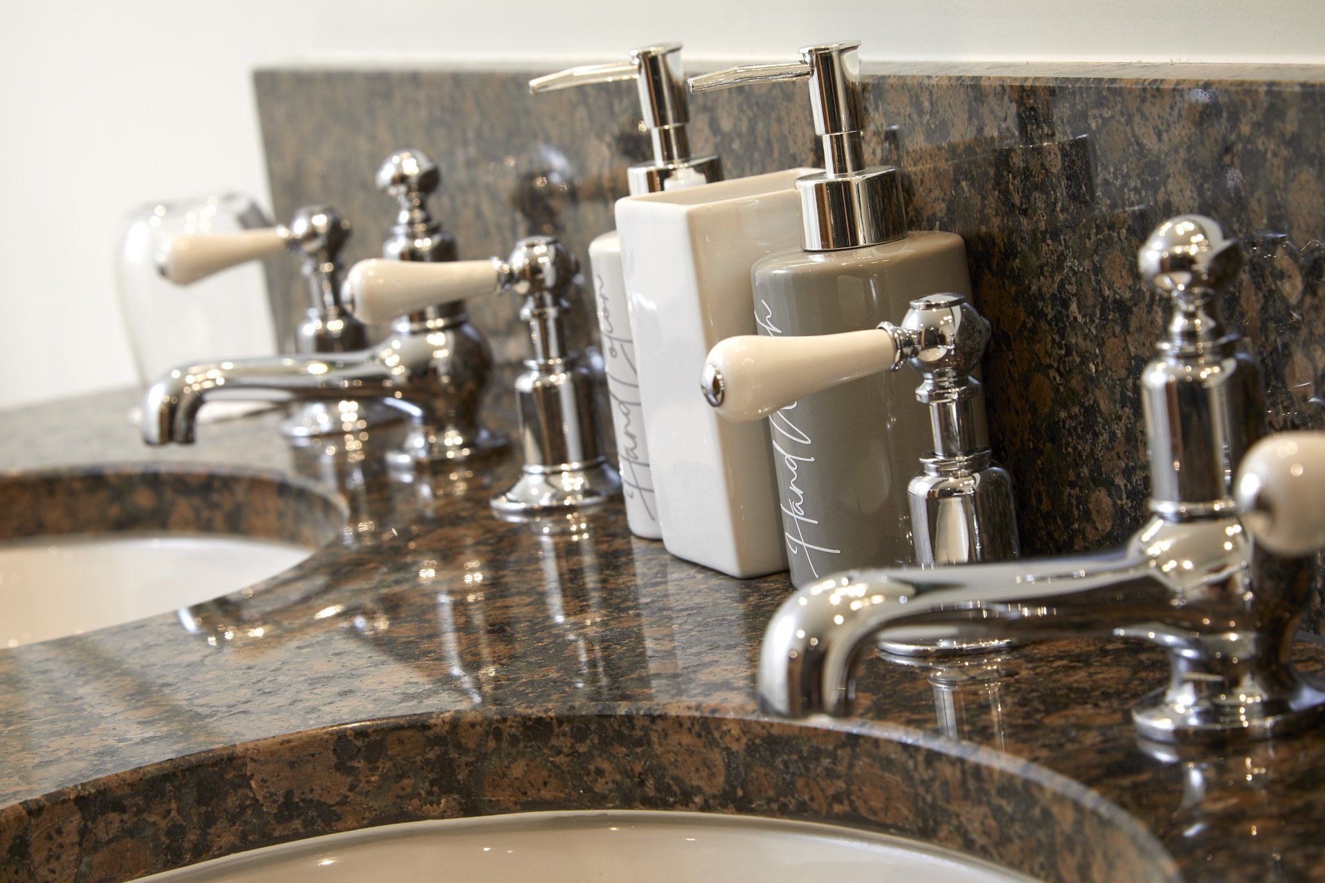A bathroom sink with soap dispensers and faucets