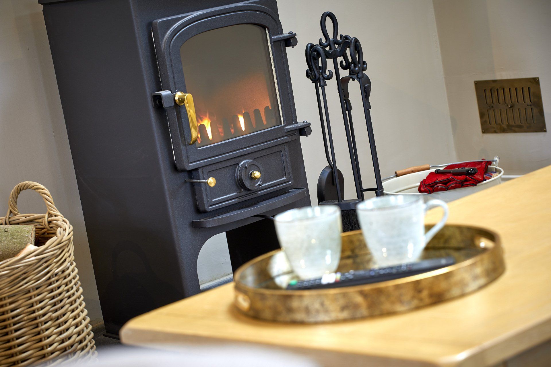 A wood stove with two cups of coffee on a tray in front of it.