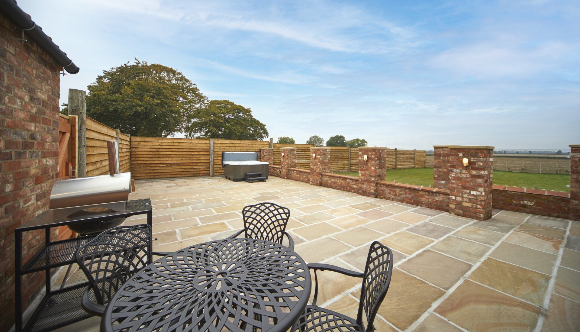 A patio with a table and chairs and a hot tub.