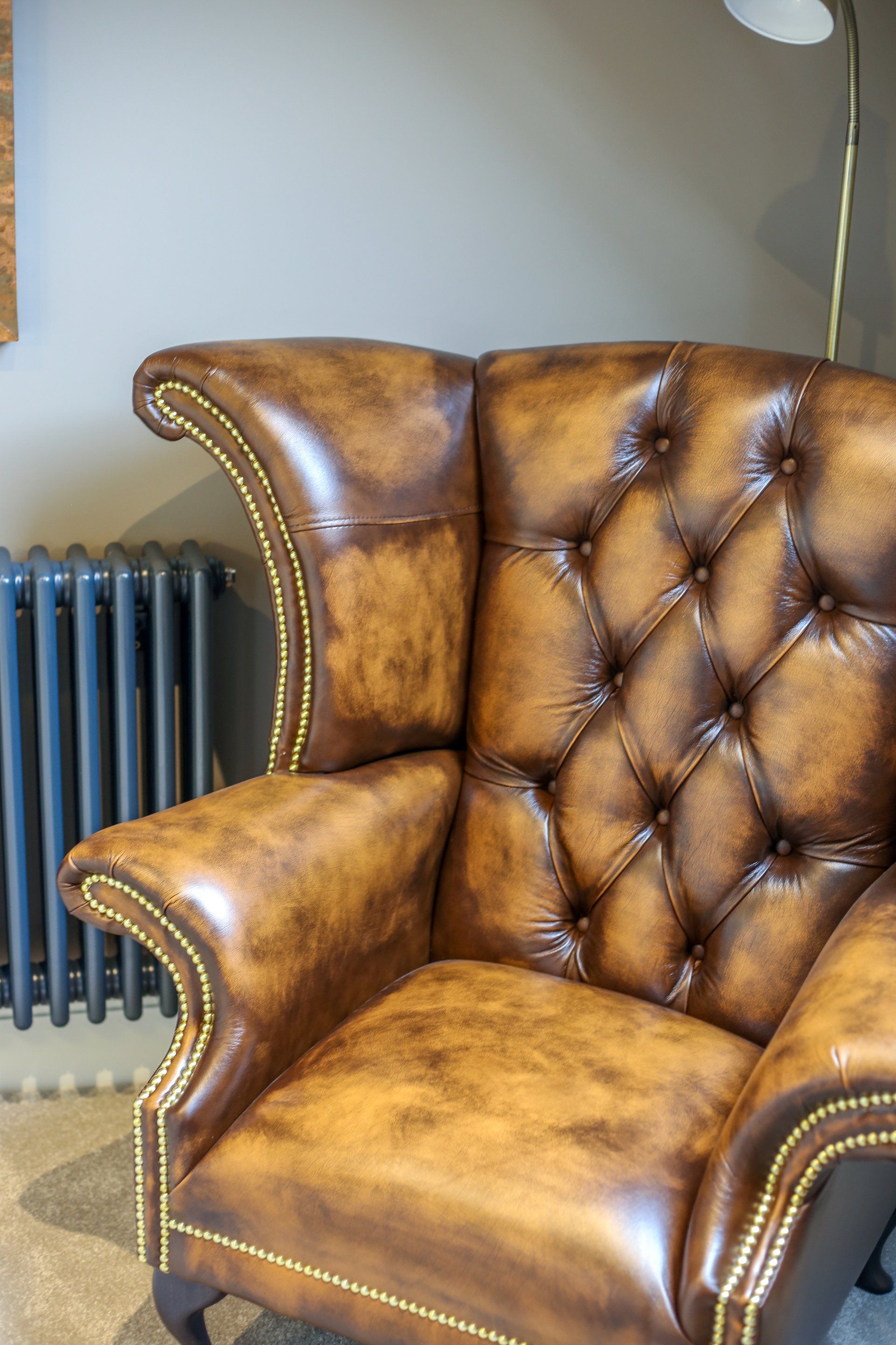 A brown leather chair is sitting in a living room next to a radiator.