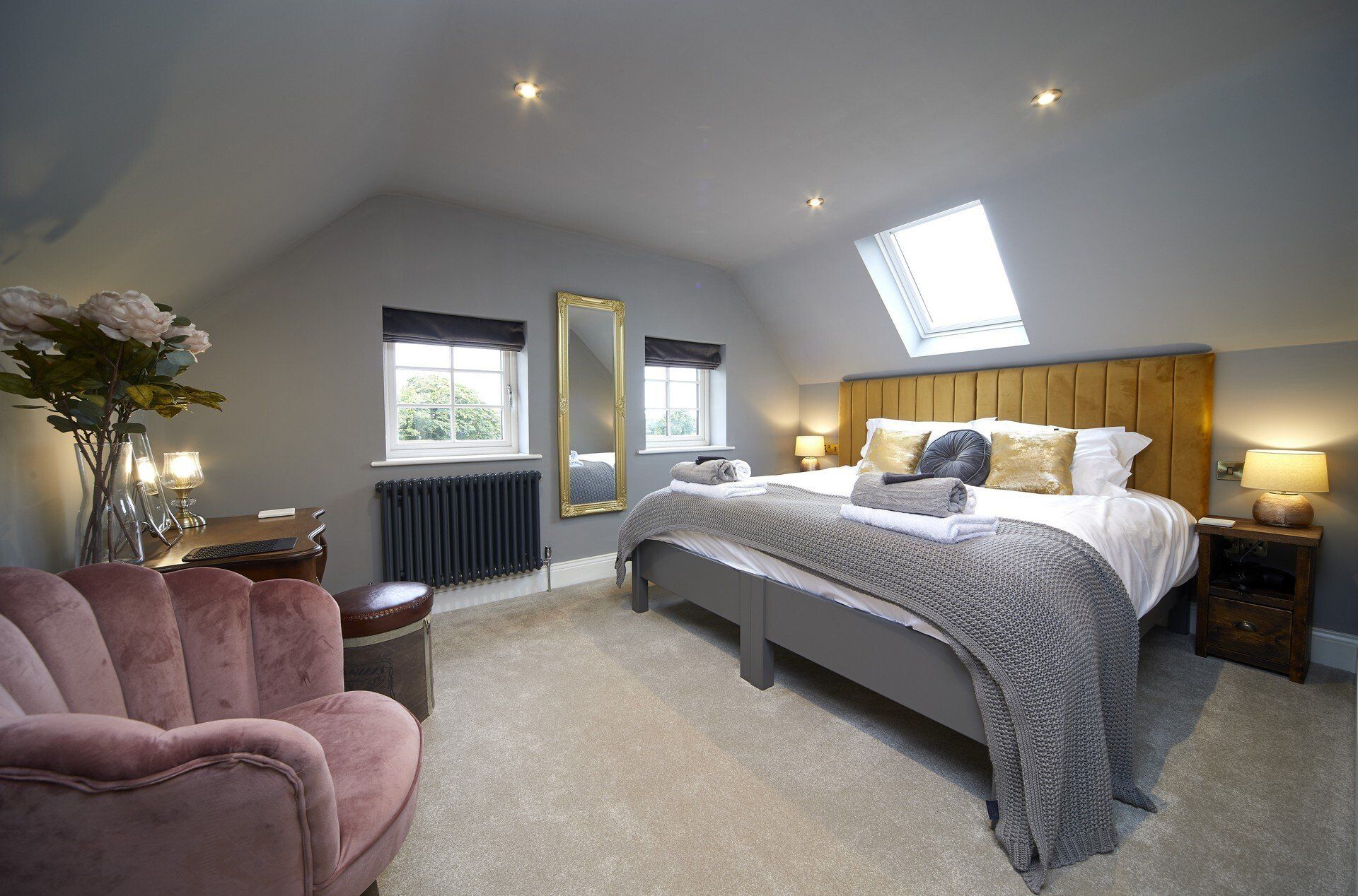 A bedroom with a large bed and a pink chair.