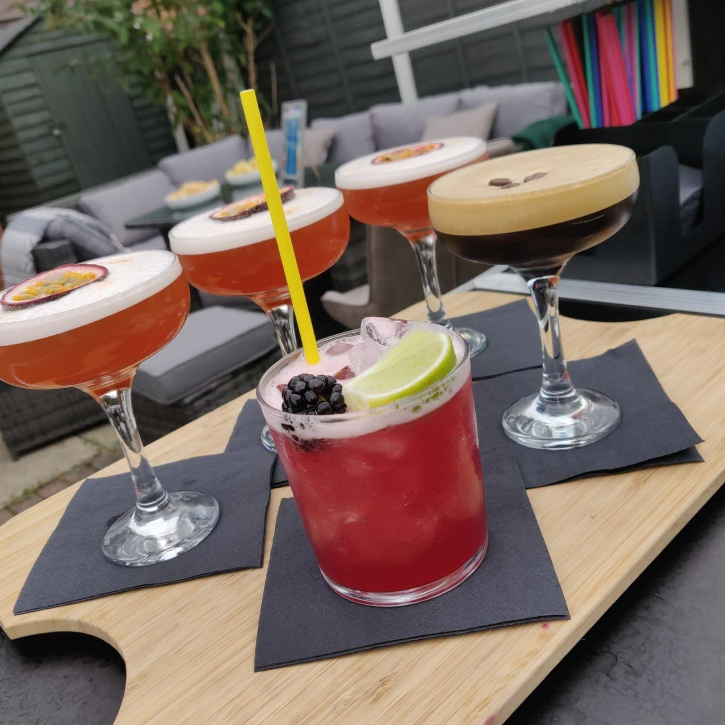 A wooden tray with a variety of cocktails on it