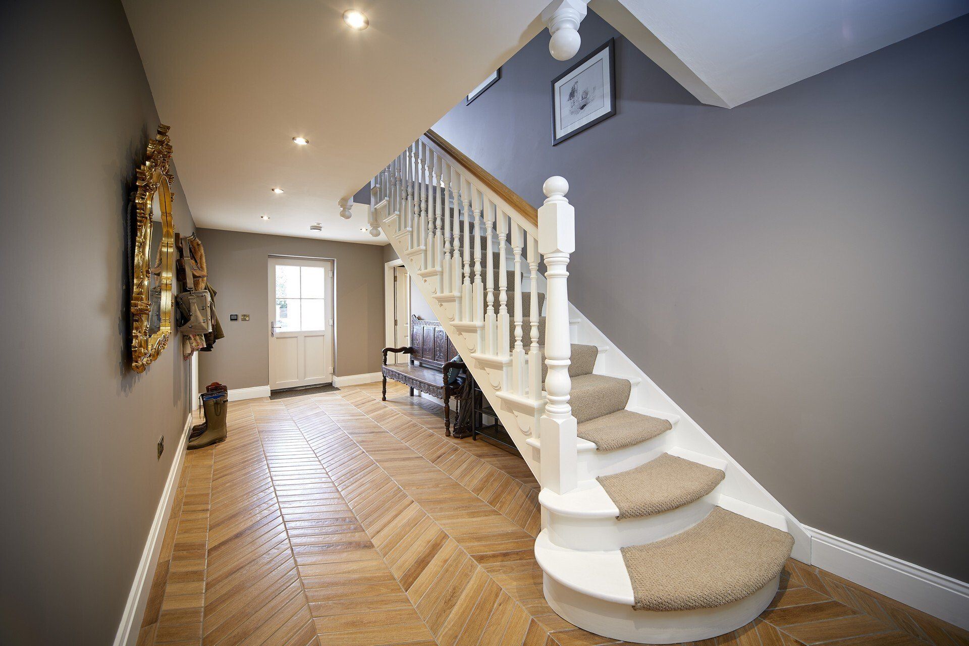 A hallway with a staircase and a bench in it.