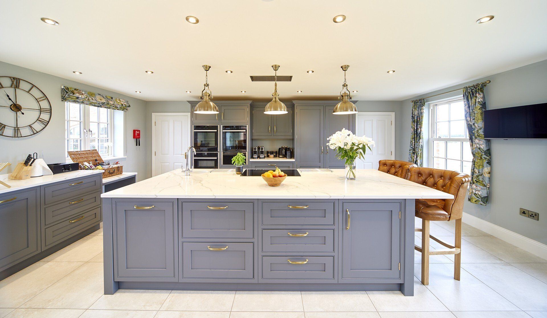 A large kitchen with a large island and a clock on the wall.