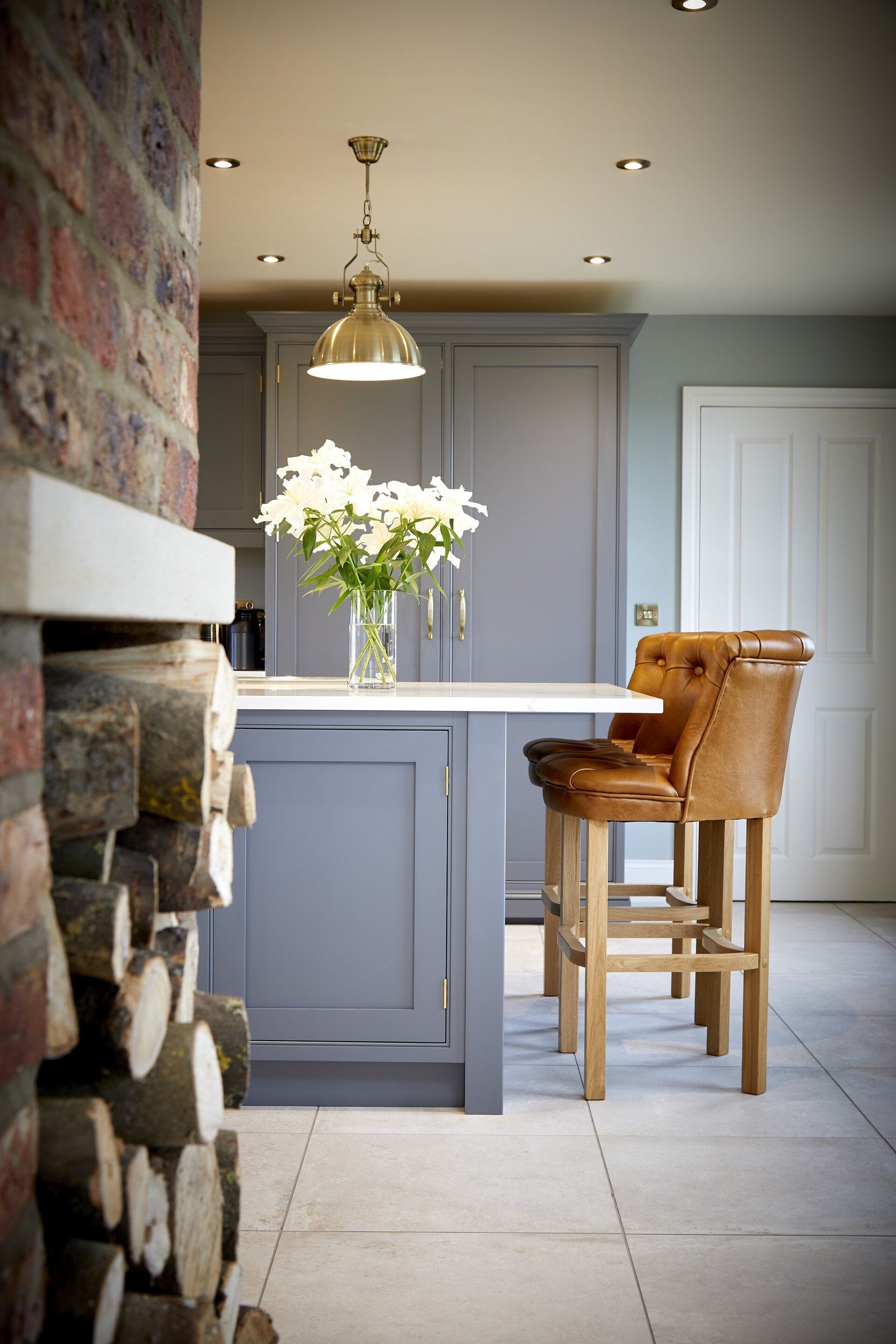 A kitchen with a fireplace and a vase of flowers on the counter.