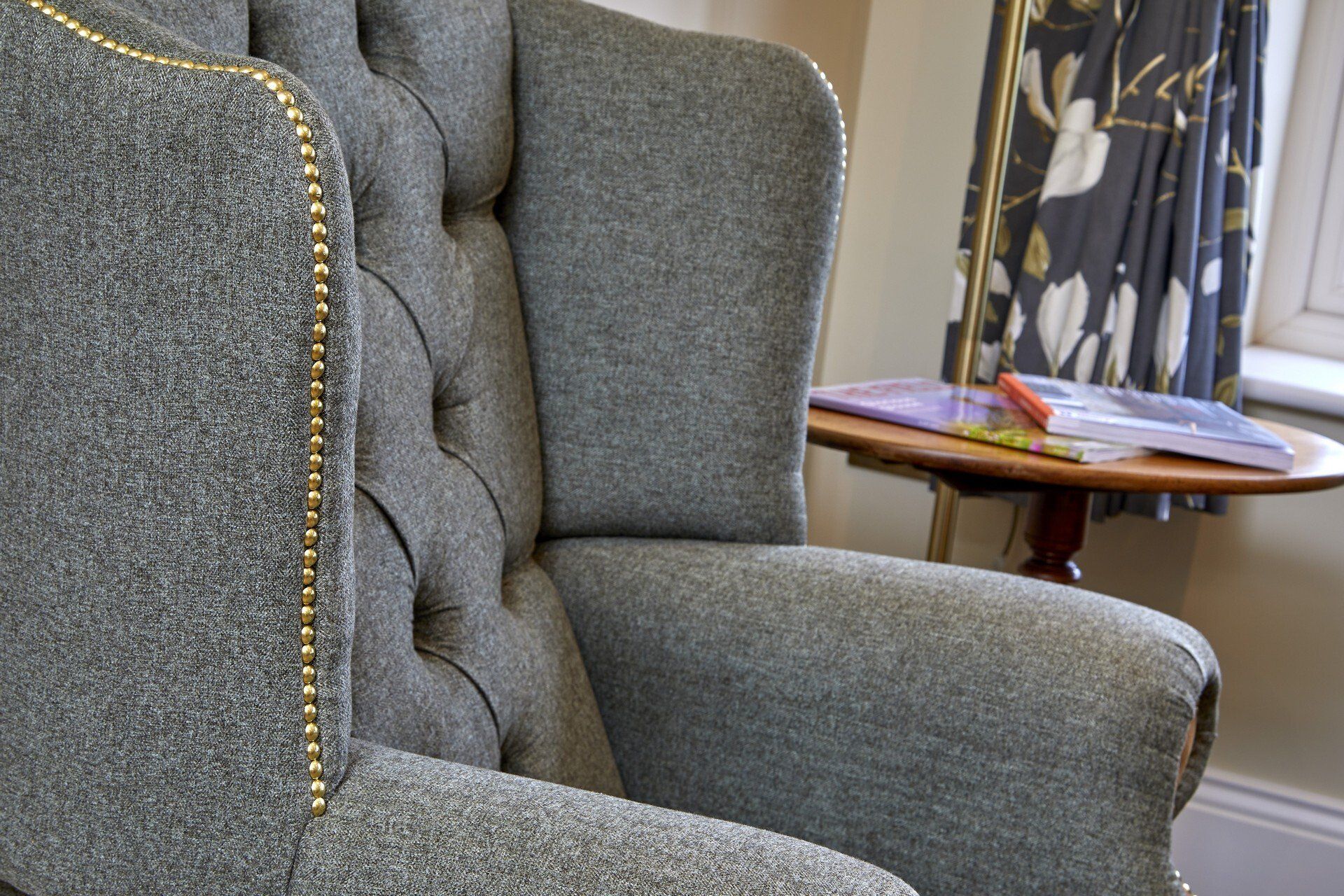 A grey chair is sitting next to a small table with a book on it.