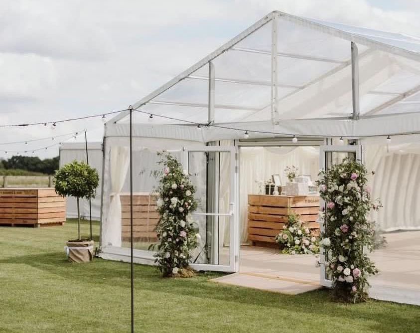 A clear tent is sitting on top of a lush green field.