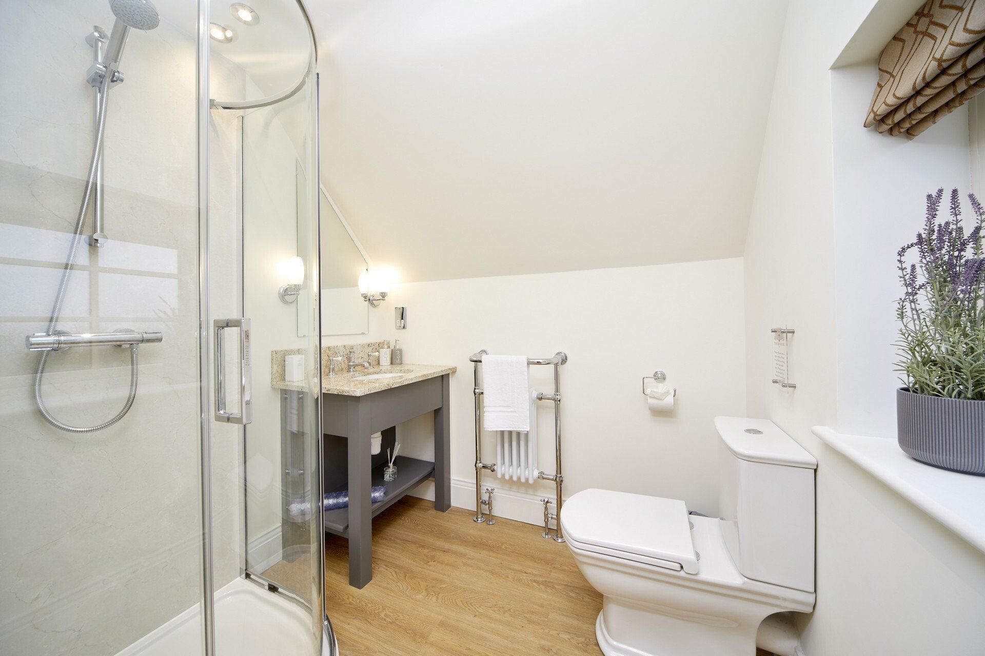 A bathroom with a toilet , sink , shower and window.