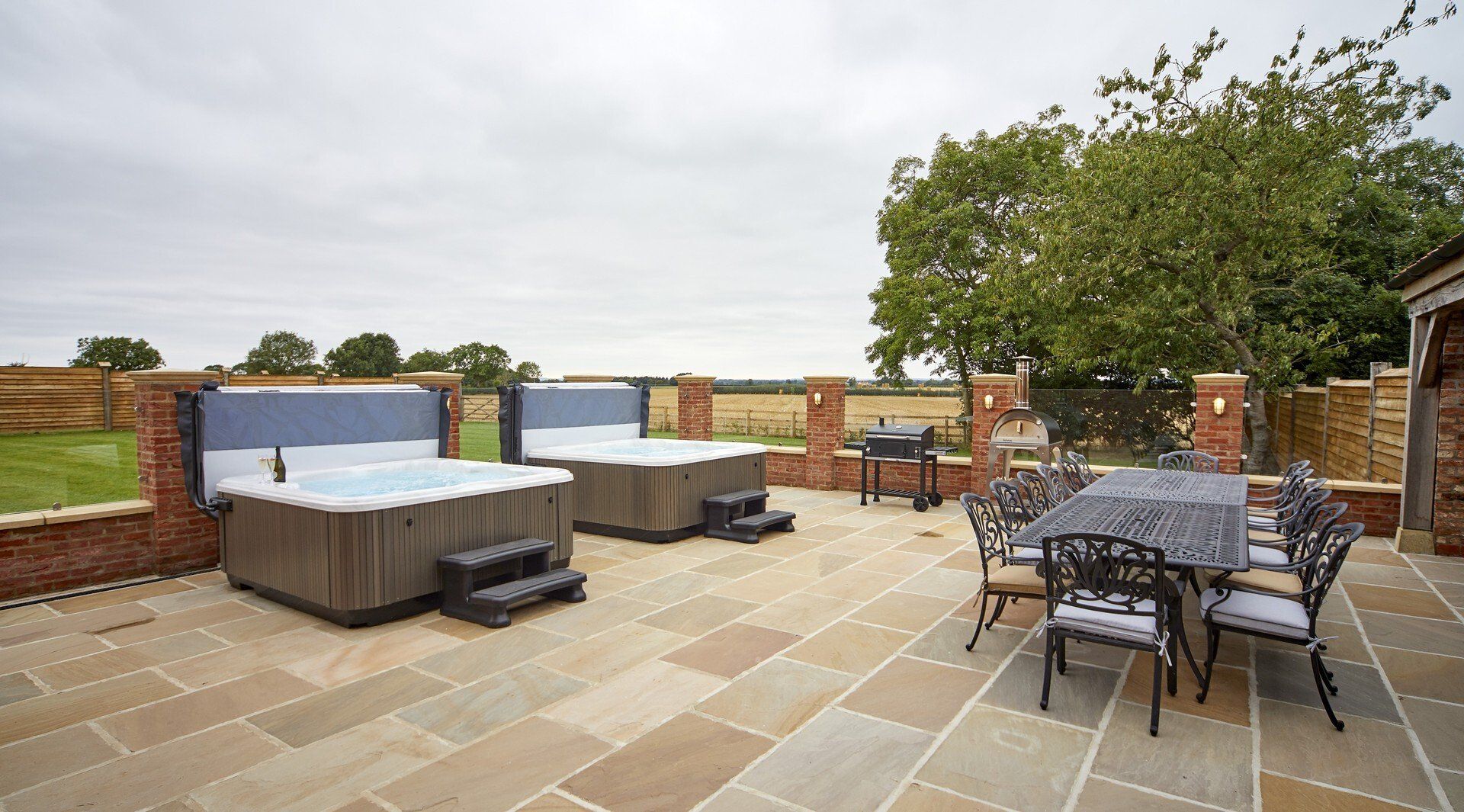 A patio with two hot tubs and a table and chairs.