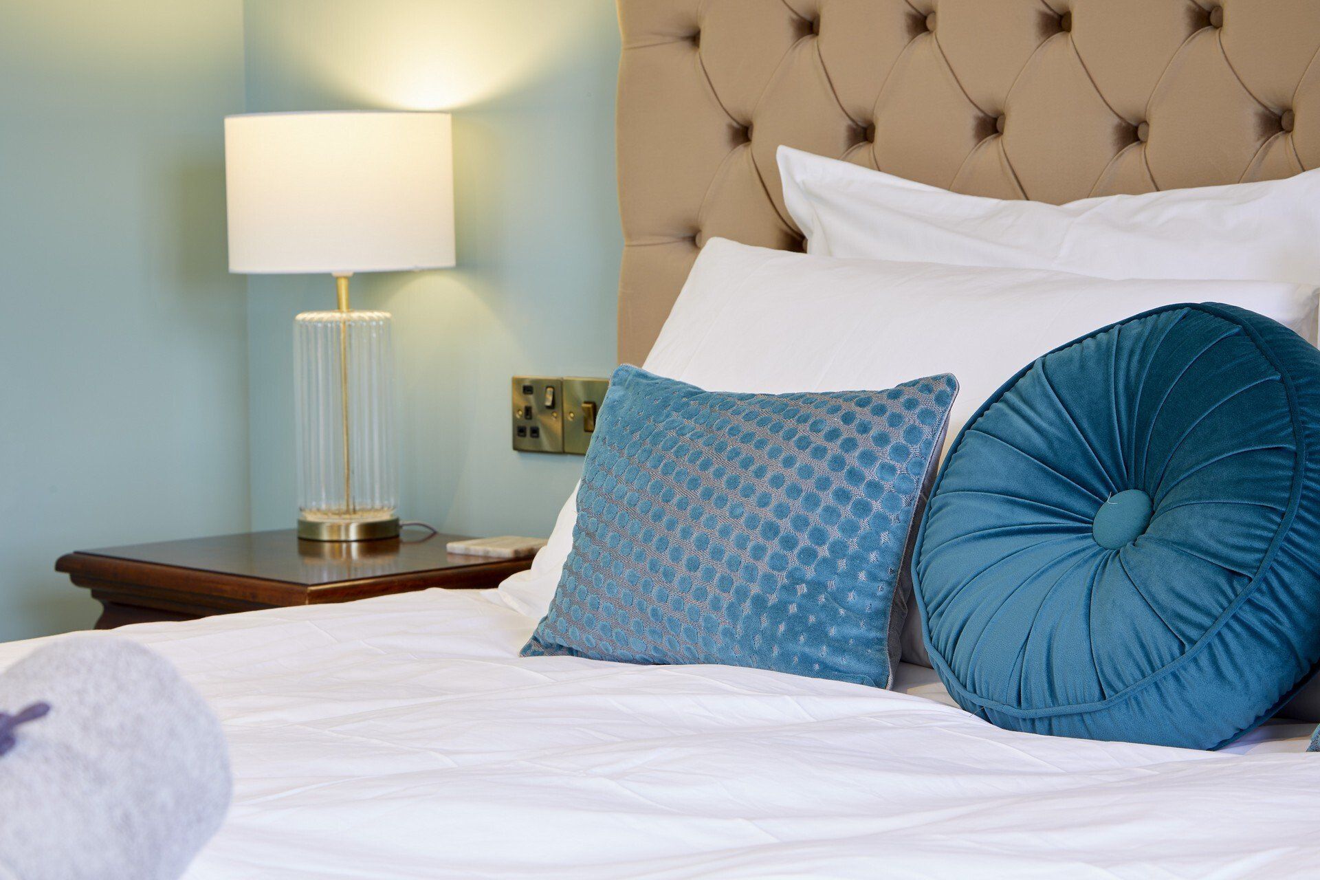 A bed with blue pillows and a lamp on it