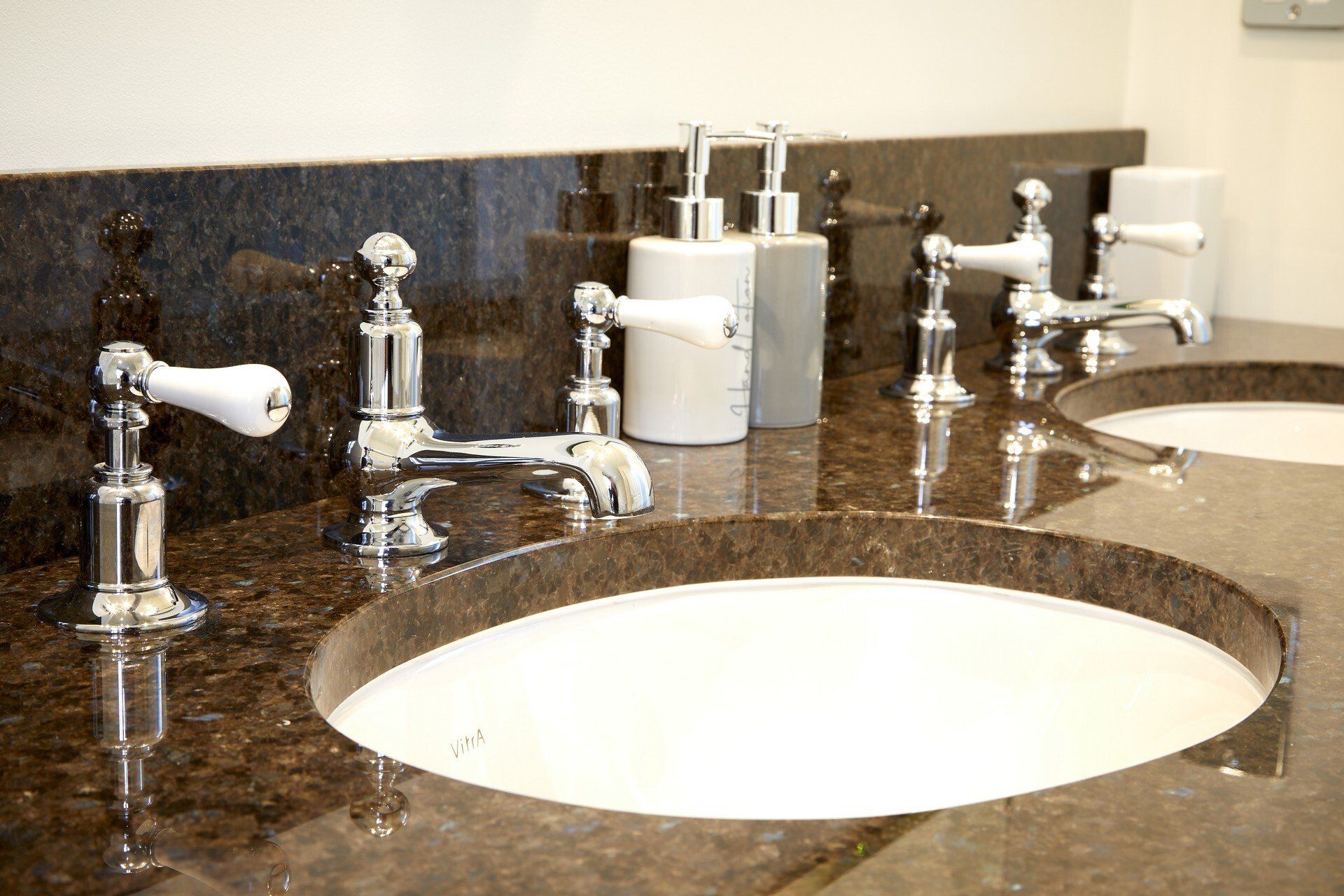 A bathroom with two sinks and soap dispensers on the counter.