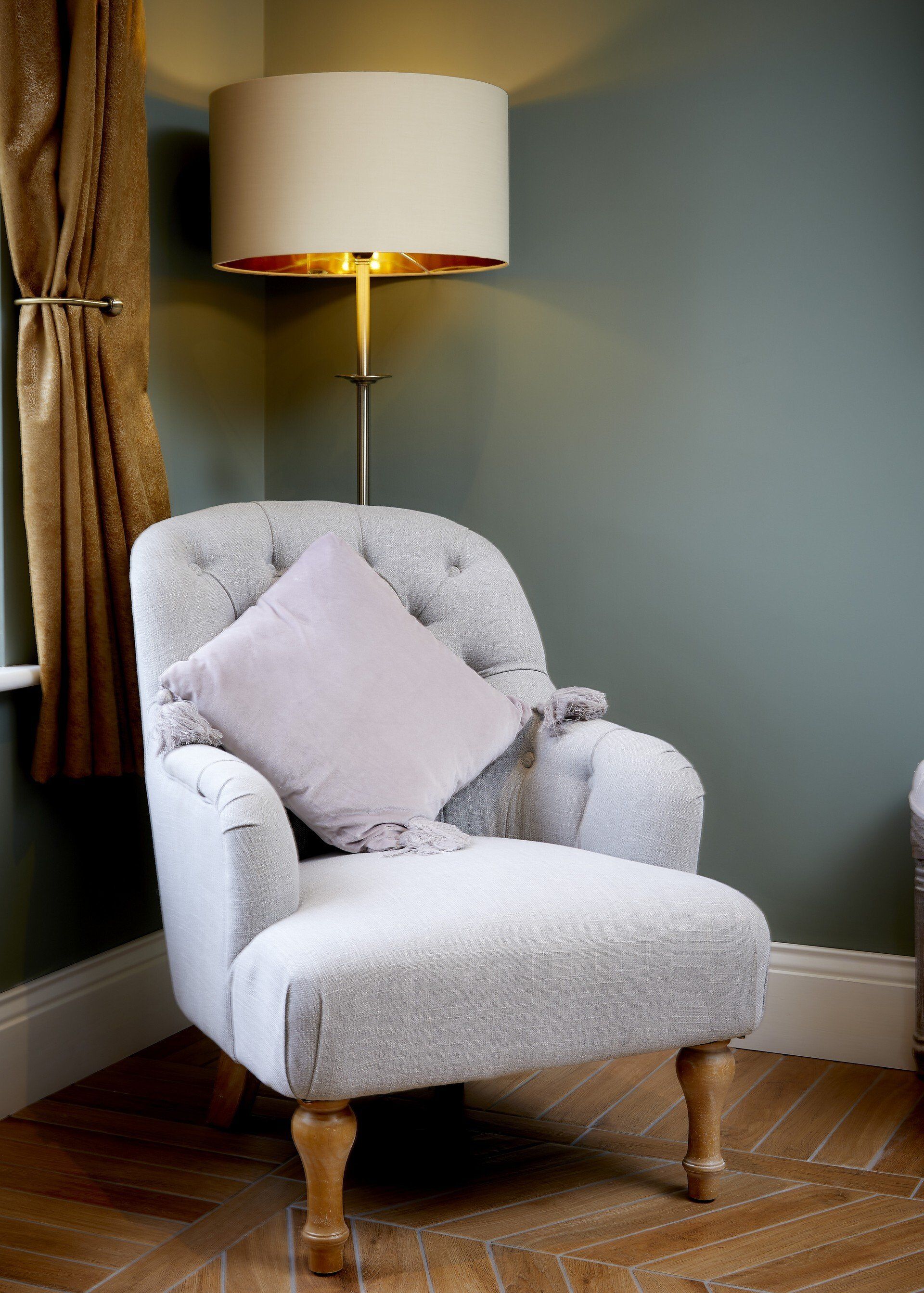 A chair with a pillow on it is in a room next to a lamp.