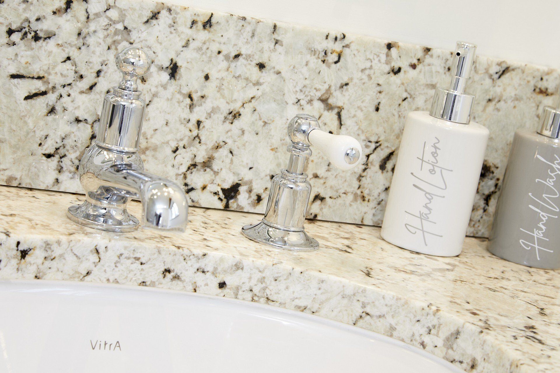 A bathroom sink with a bottle of hand lotion on the counter