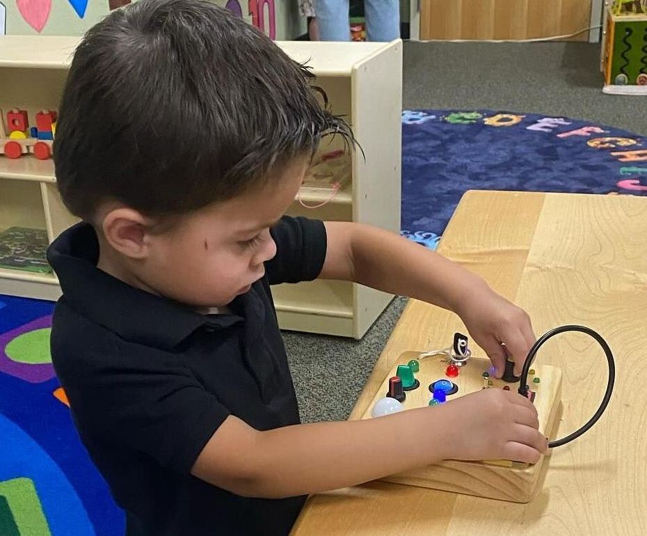 A young boy is playing with a wooden toy on a table.
