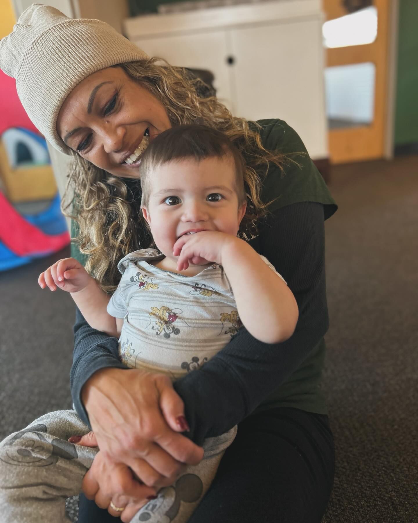 A woman is holding a baby in her arms and smiling.