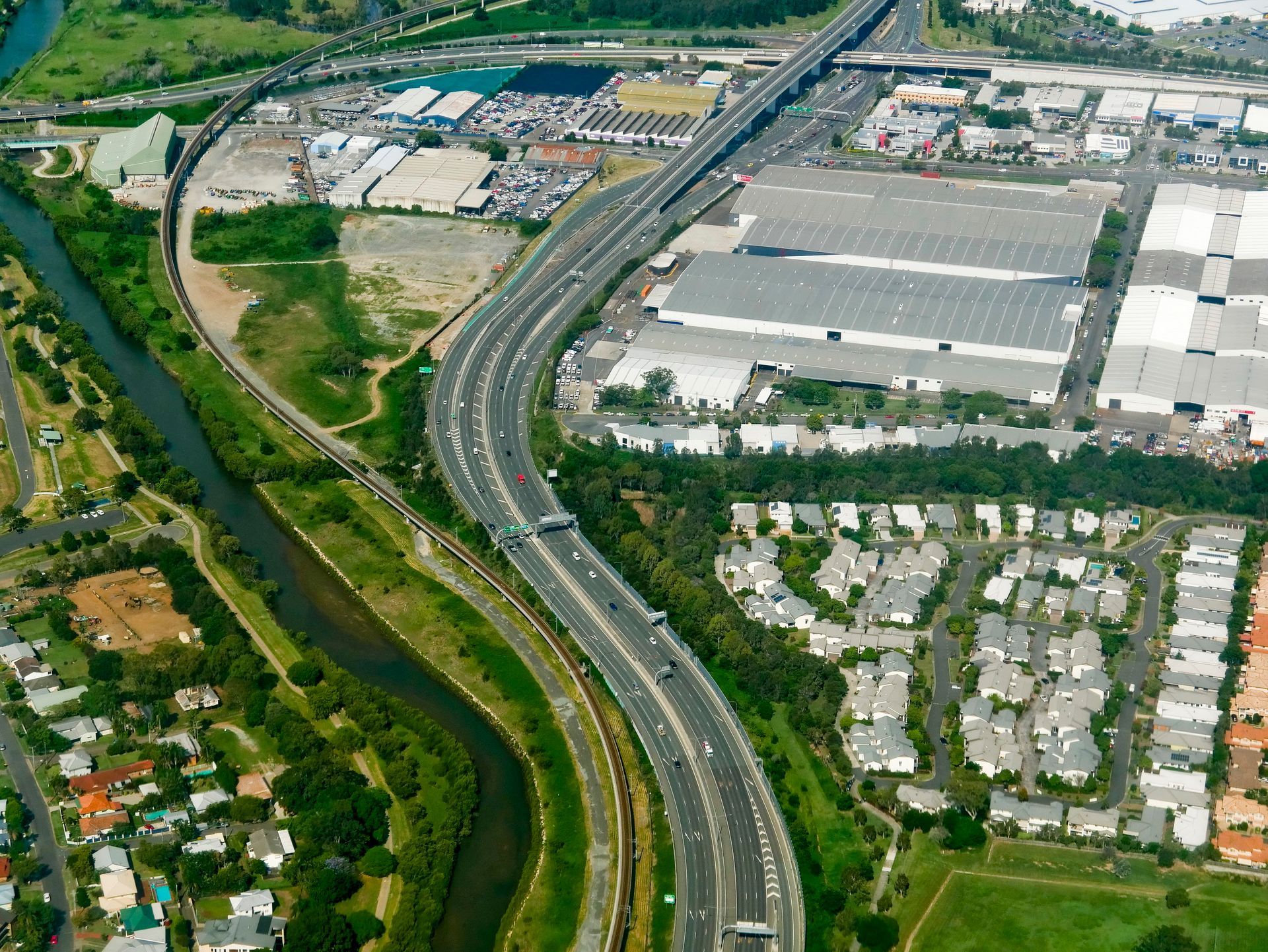 Aerial View: Highway Curves Alongside a River and Residential Area โ J'adore Flowers & Gifts Cairns in Bungalow, QLD