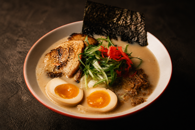 Ramen bowl with sliced pork, soft-boiled egg halves, seaweed, and green onions