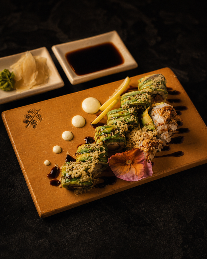 Gourmet plated skewers with green herb sauce, sauce dots, fries, and dipping bowls on a dark table