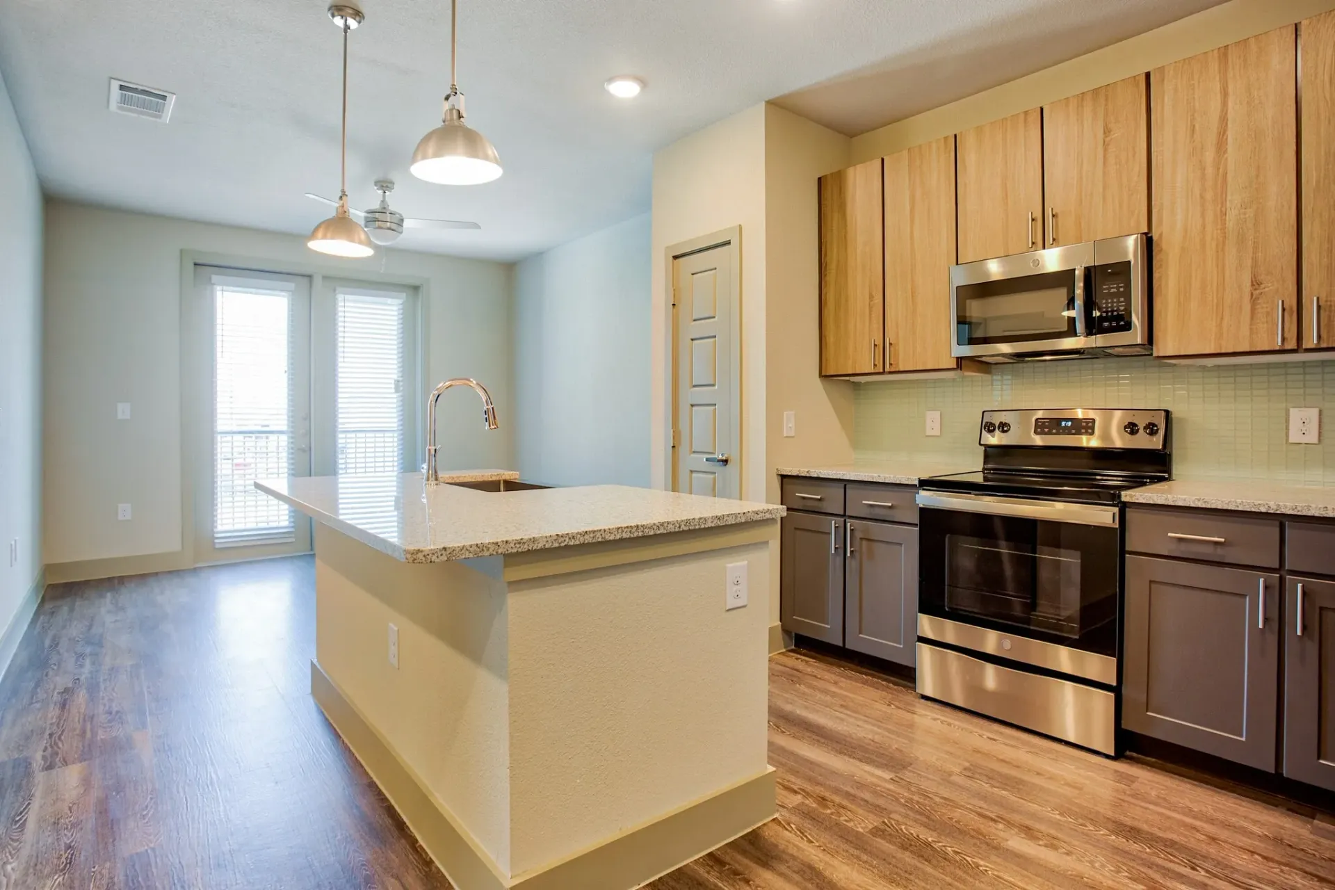 Modern kitchen with natural wood cabinetry and stainless-steel appliances in a model home at Three77 Park in Fort Worth, TX.