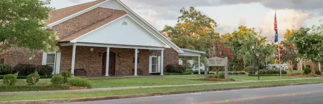 The front door of a house with a porch and plants in front of it.