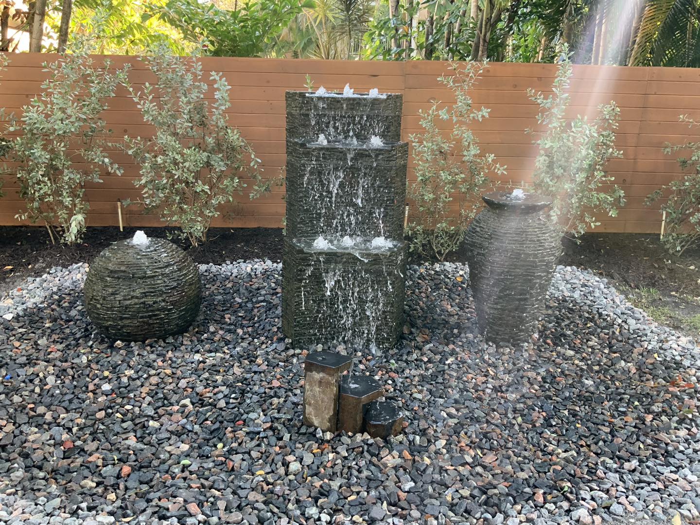Water fountains in a gravel bed; includes stone spheres and a tiered fountain.