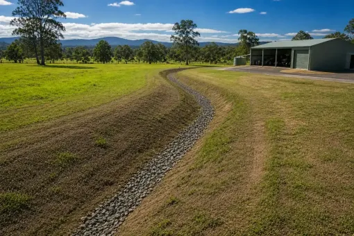 Gravel drainage channel across an open rural Cairns property.