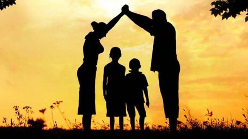 A silhouette of a family holding hands in the shape of a house.