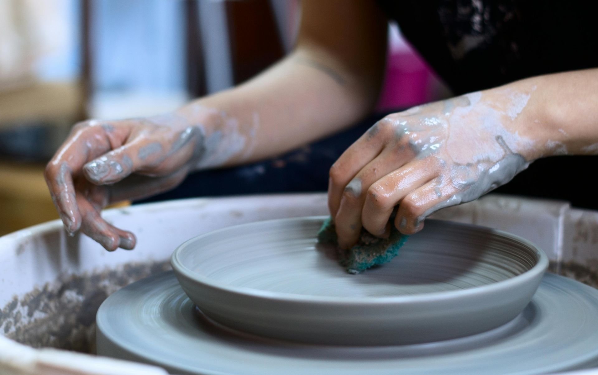 A person is making a plate on a pottery wheel.