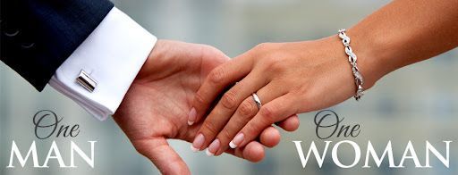 A man and a woman are holding hands with their wedding rings on