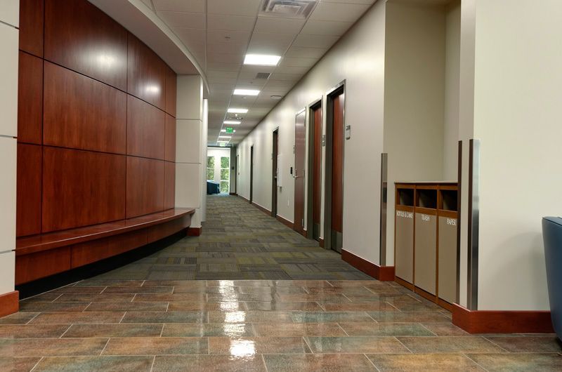 Hallway with wood paneling, brown doors, and a tiled floor.