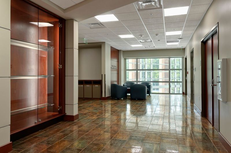 Hallway with dark wood cabinets, glossy tile floor, seating area with large windows, and recessed lighting.