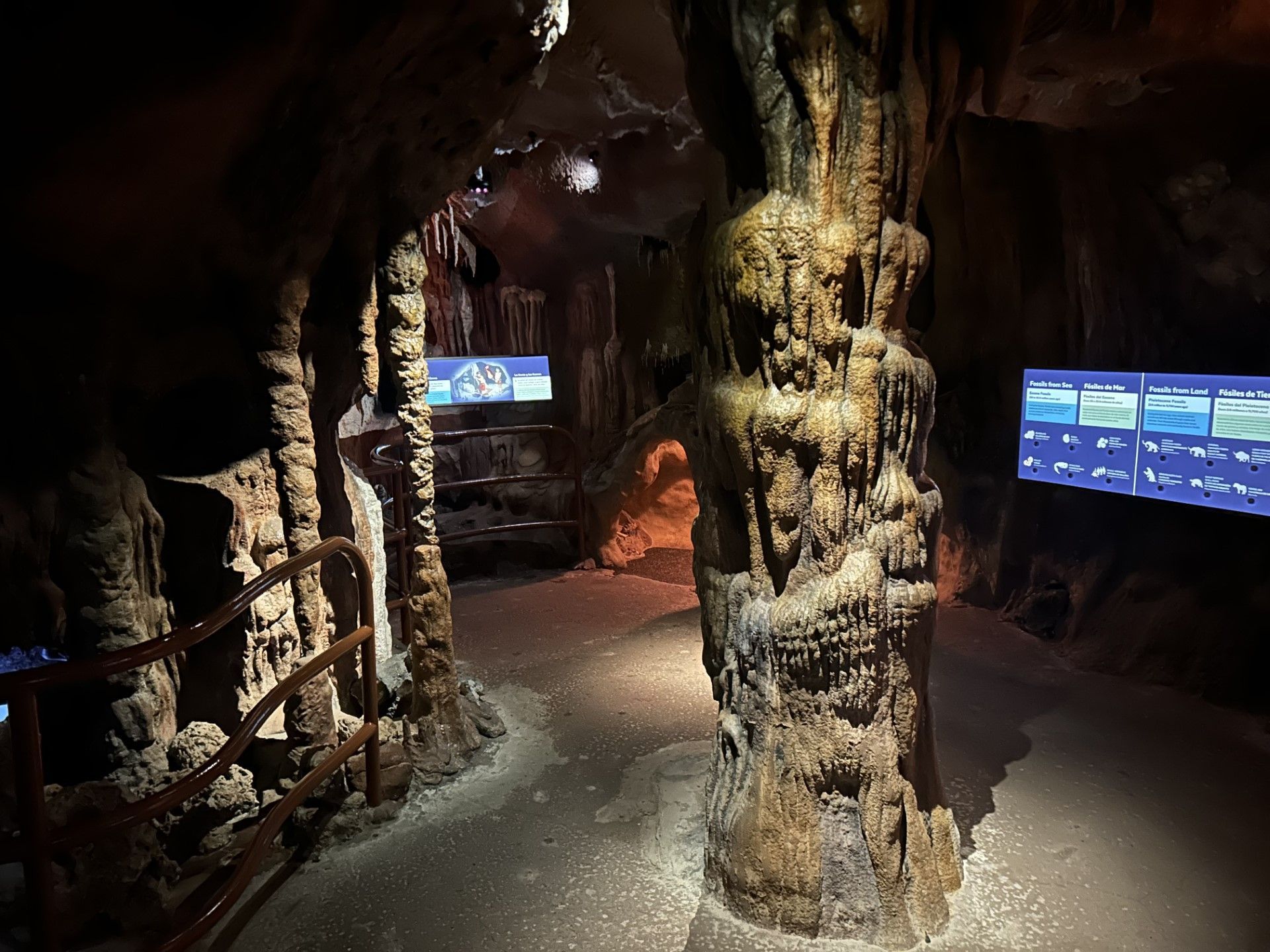 Cave interior with formations, lit path, displays.