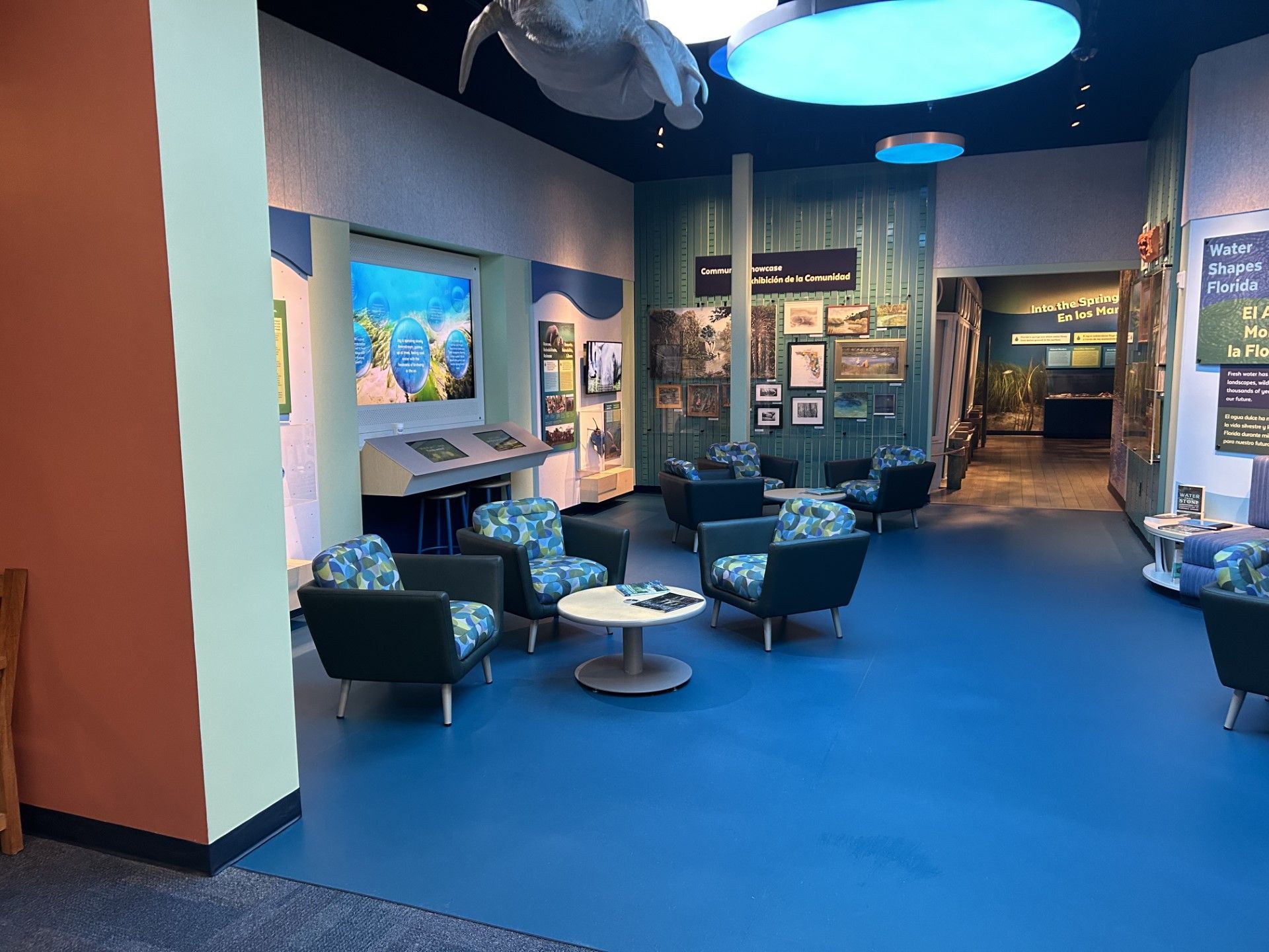 Museum interior with blue floor, armchairs, display cases, and informational signage.