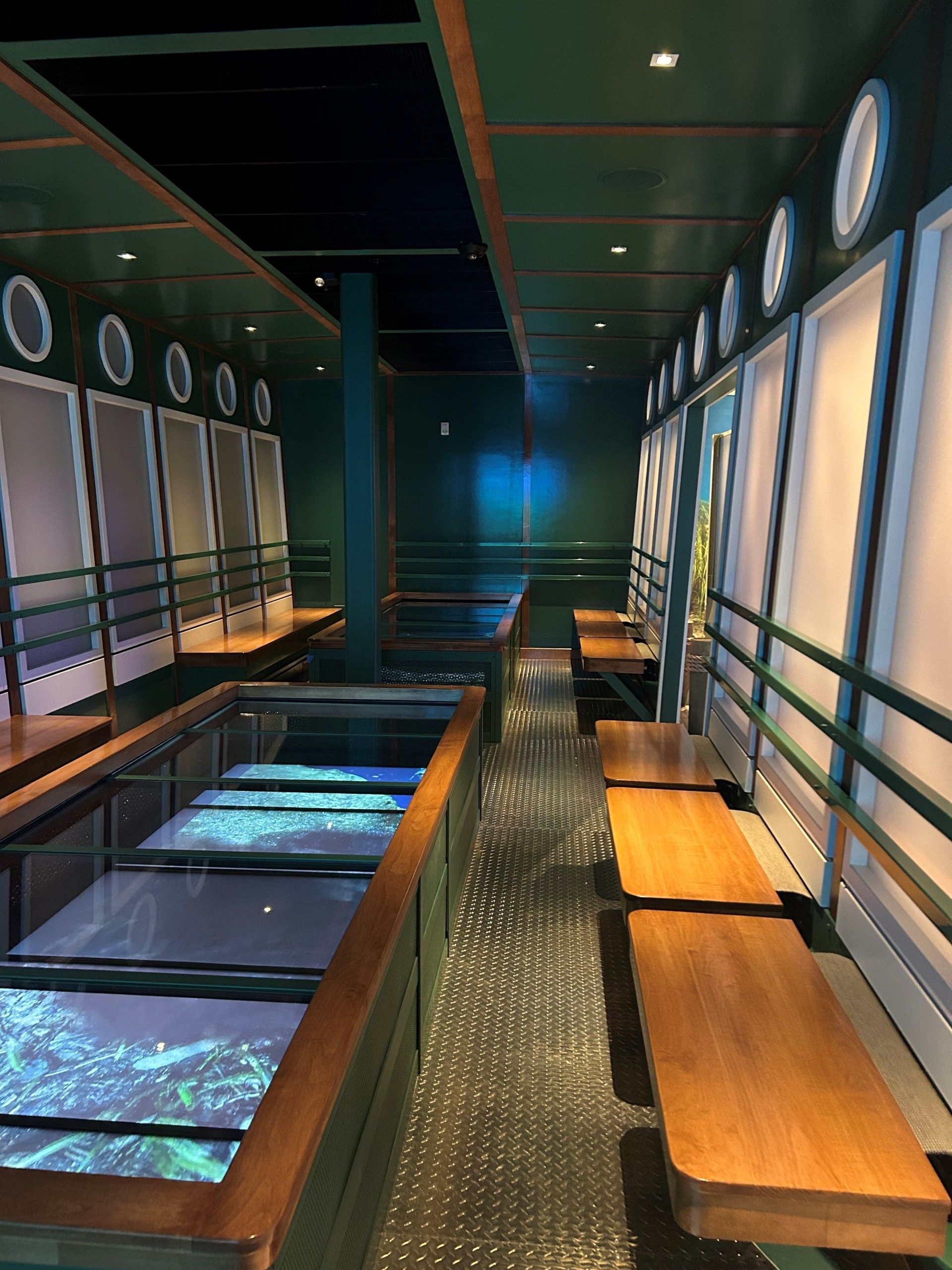 Interior of a restaurant designed to look like a ship. Green walls, porthole windows, water features on the floor.