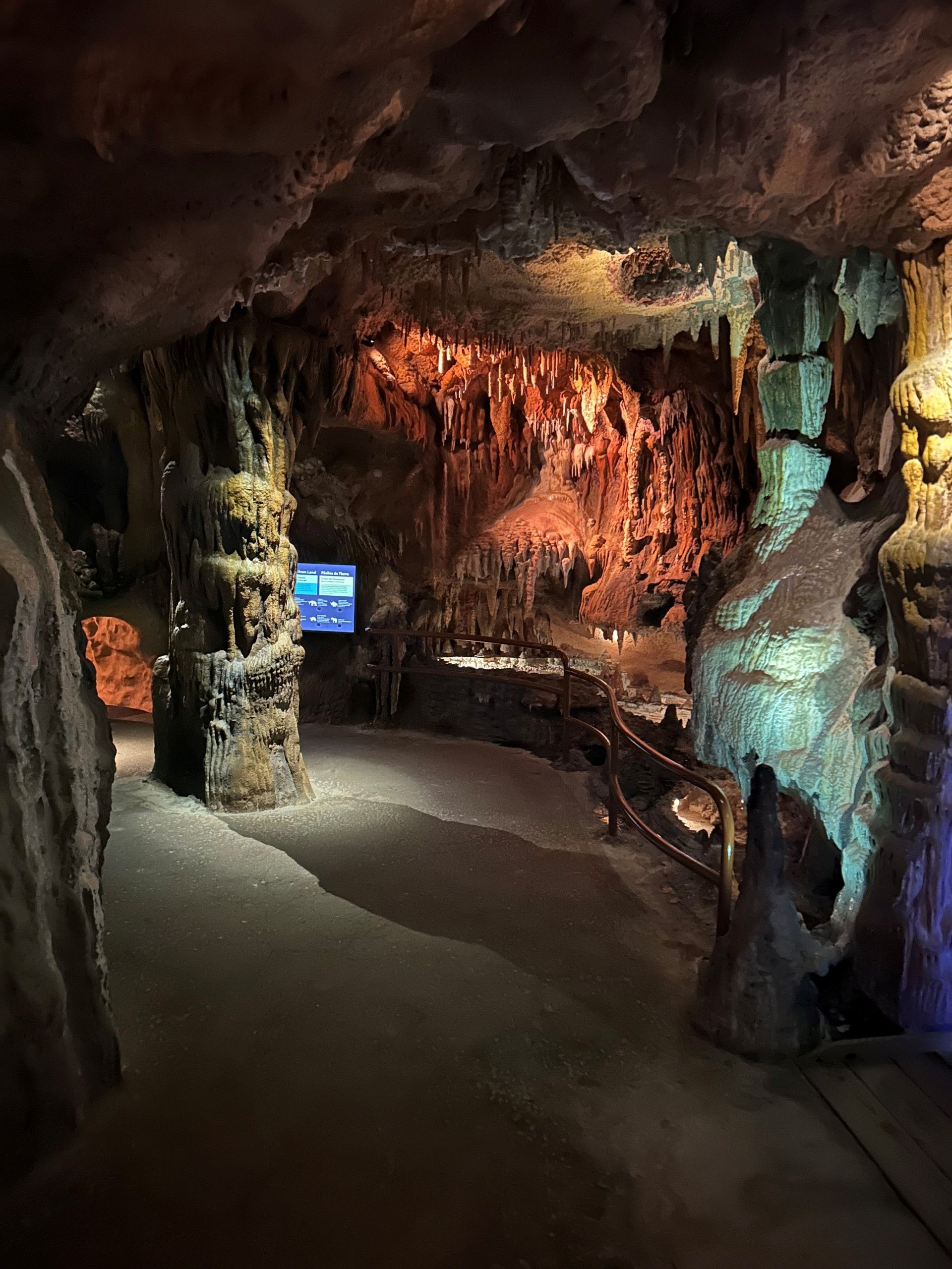 Cave interior with illuminated rock formations, walkways, and wooden railings.