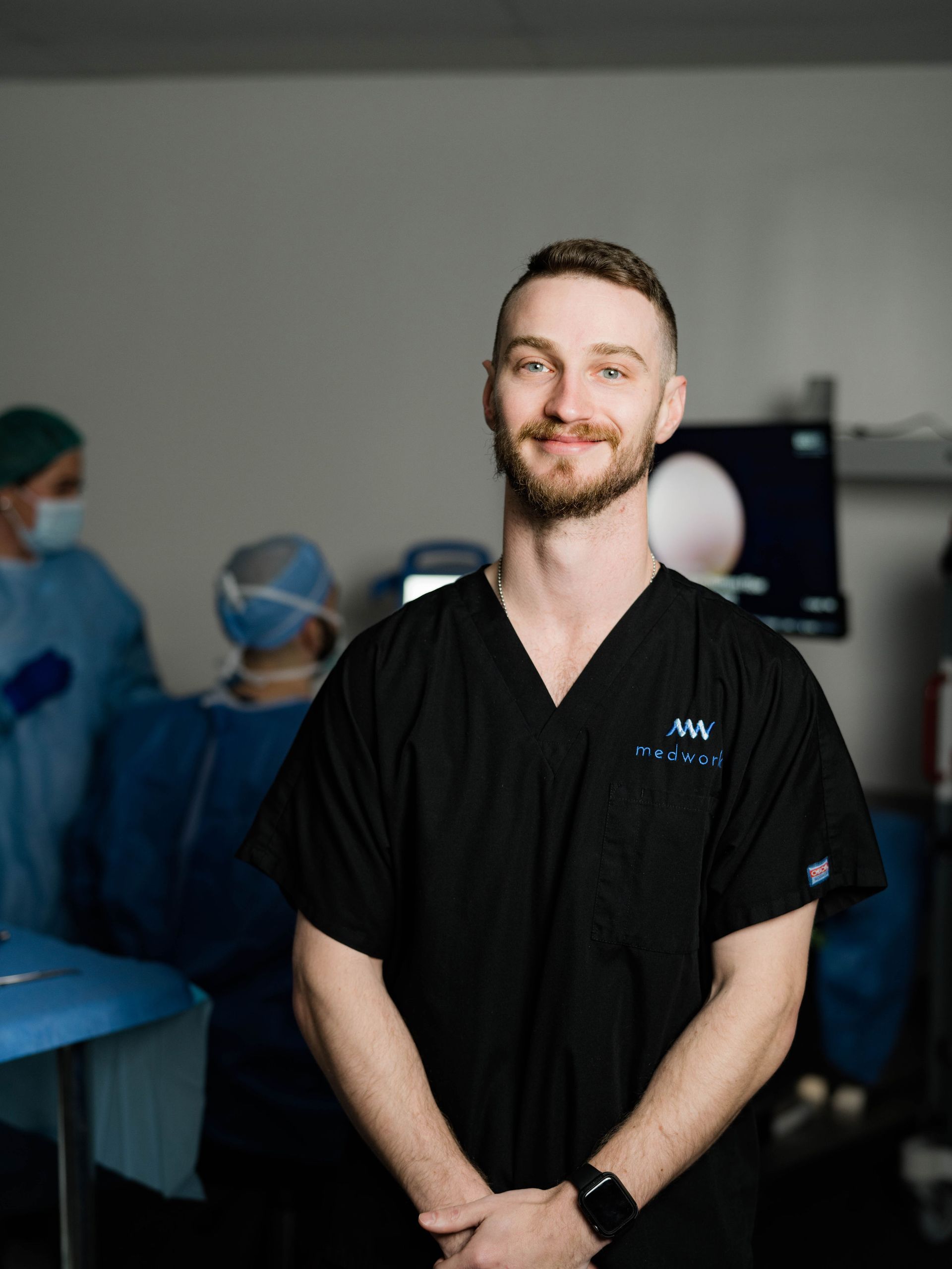 A man in a black scrub is standing in a hospital room