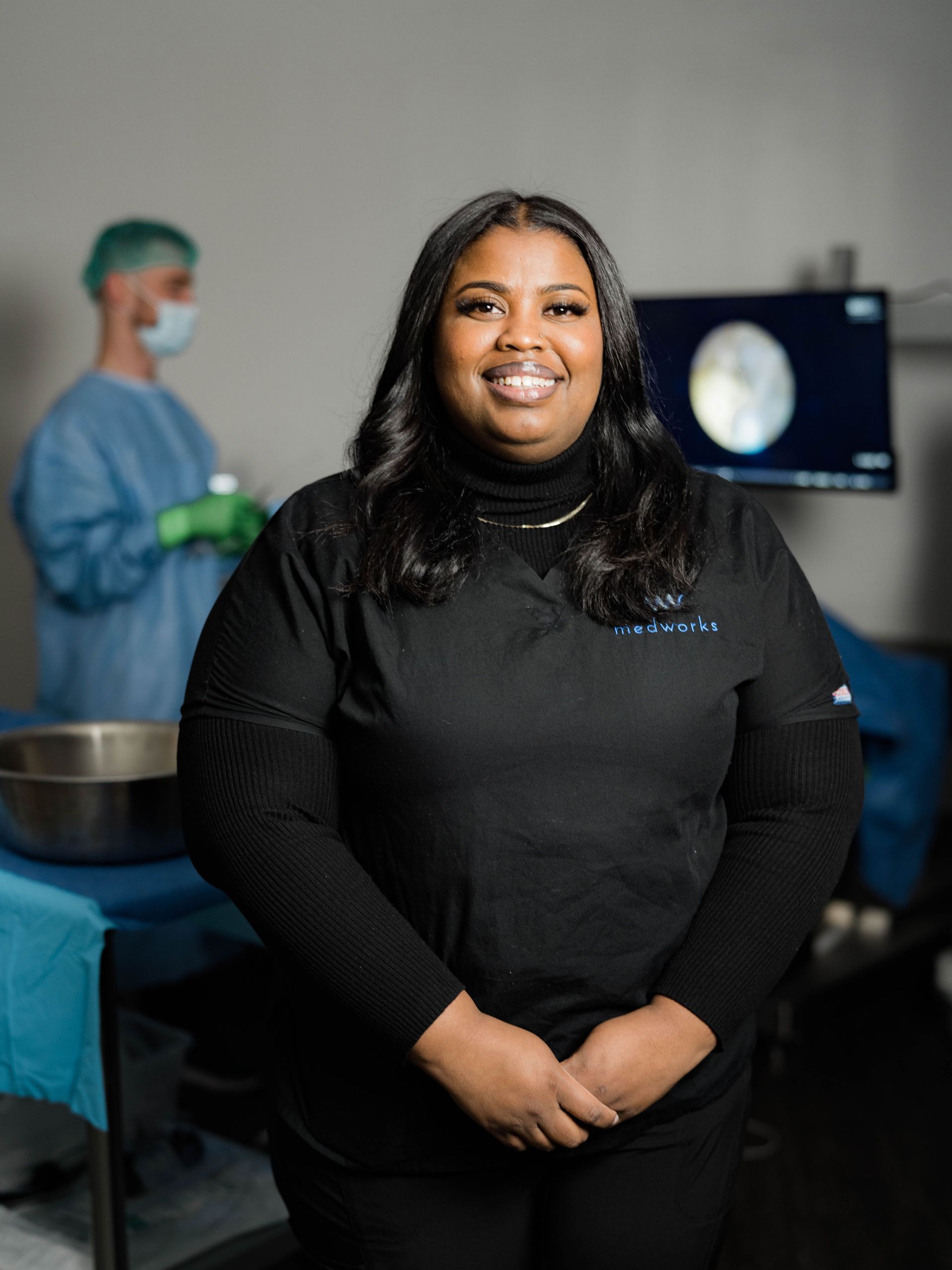 A woman in a black shirt is posing for a picture in a surgical room.
